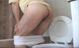 Skinny guy pooping a big one over toilet